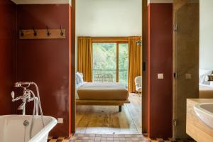 a bathroom with a tub and a bed and a window at Rooms Hotel Kazbegi in Kazbegi