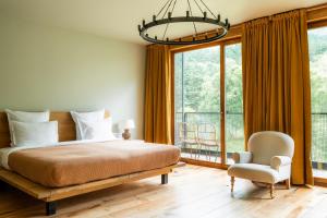 a bedroom with a bed and a chair and a large window at Rooms Hotel Kazbegi in Kazbegi