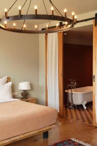 a bedroom with a bed and a bath tub and a chandelier at Rooms Hotel Kazbegi in Stepantsminda
