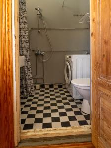 a bathroom with a toilet and a checkered floor at Koskivaara - vanha koulu - old school in Huutotöyry