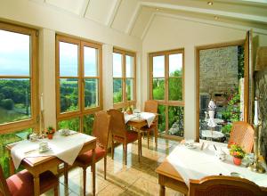 ein Restaurant mit Tischen, Stühlen und Fenstern in der Unterkunft Burghotel in Rothenburg ob der Tauber