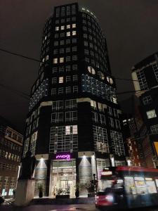 un grand bâtiment avec un panneau sur lui la nuit dans l'établissement Moxy The Hague, à La Haye