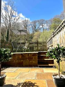 a patio with two chairs and an umbrella at Hollins Cottage. Central location, Marple Bridge in Marple