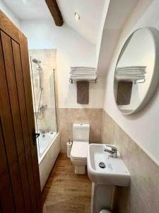 a bathroom with a sink and a toilet and a mirror at Hollins Cottage. Central location, Marple Bridge in Marple