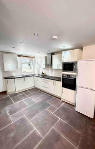 a kitchen with white appliances and a tile floor at Hollins Cottage. Central location, Marple Bridge in Marple