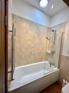 a bathroom with a bath tub with a shower at Hollins Cottage. Central location, Marple Bridge in Marple