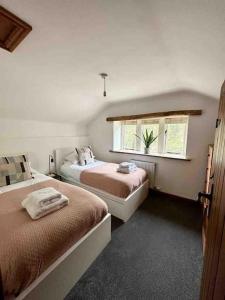 a bedroom with two beds and a window at Hollins Cottage. Central location, Marple Bridge in Marple