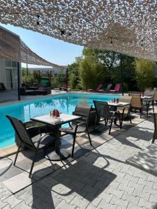 un patio avec des tables et des chaises à côté d'une piscine dans l'établissement Hotel La Clé, à Saint-André-de-Sangonis
