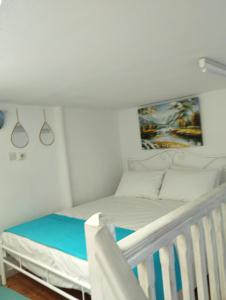 a white bedroom with a bed and a crib at Mari...Milo in Péran Triovasálos