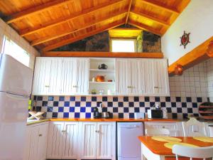 a kitchen with white cabinets and black and white tiles at Casa do Guardião in Madalena