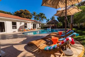 a swimming pool with lounge chairs and an umbrella at Pineapple Palms Resort Style Pool Villa! Sleeps 12 in West Palm Beach