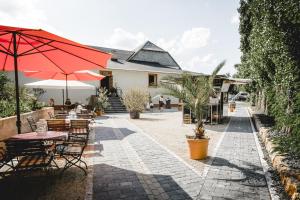 un patio con mesas, sillas y una sombrilla en Klostermühle, en Eltville am Rhein