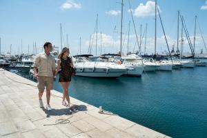 Ein Mann und eine Frau stehen auf einem Dock mit Booten. in der Unterkunft Taranto in barca Boat and Breakfast in Taranto
