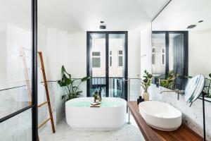 ein Badezimmer mit einer weißen Badewanne und einem Waschbecken in der Unterkunft Juno Hotel Sofia, a Member of Design Hotels in Sofia