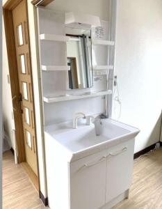 y baño con lavabo blanco y espejo. en メゾンドヴィラ, en Kami-furano