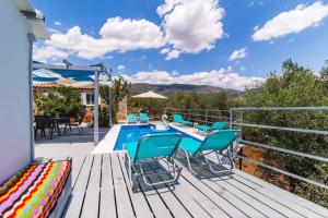 una terraza con sillas azules y una piscina en Artemis Cottage Home, en Fréngaina