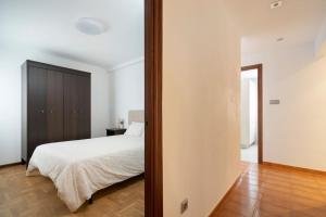 a bedroom with a white bed and a wooden floor at MyHouseSpain - Único piso cerca de la playa in Gijón