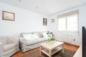a white living room with a white couch and a table at MyHouseSpain - Único piso cerca de la playa in Gijón