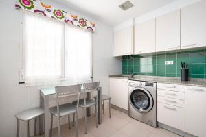 a kitchen with a table and chairs and a washing machine at MyHouseSpain - Único piso cerca de la playa in Gijón