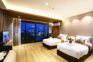 una camera d'albergo con due letti e un divano di Montana Hotel Songkhla a Songkhla