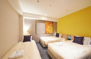 2 łóżka w pokoju z żółtymi ścianami w obiekcie Sotetsu Grand Fresa Osaka-Namba w Osace