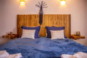 um quarto com uma cama azul, uma cabeceira e almofadas de madeira em Casa da Cerca em Sortelha