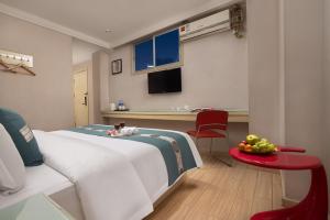 um quarto com uma cama e uma mesa com uma tigela de fruta em Kaiserdom Hotel Baiyun Airport-24-hour Airport-Free shuttle bus em Huadu