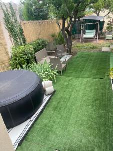 a backyard with a green lawn with a table and chairs at Maison 3chambres ,climatisée in Nîmes