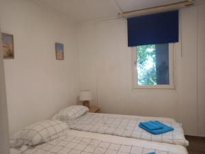 Dos camas en una habitación blanca con ventana. en Málna Privát Nyaraló, en Balatonlelle