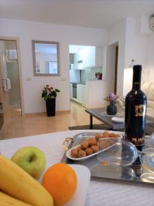 a table with a plate of fruit and a bottle of wine at Melody Apartment in Poreč