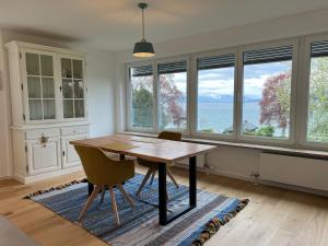 comedor con mesa, sillas y ventanas en Ferienwohnung Blümlein, en Nonnenhorn