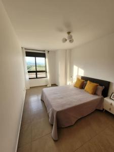 een witte slaapkamer met een groot bed met gele kussens bij Apartamento Margalló con Garaje in Xilxes