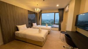 a hotel room with two beds and a flat screen tv at Sibtis Hotel in Lampang