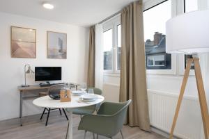 een woonkamer met een tafel en stoelen en een bureau bij Arbio I Central Apartments Koblenz in Koblenz