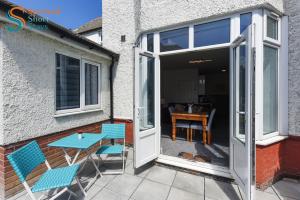 a patio with blue chairs and a table and a door at Two bedroom ground floor apartment near the beach in Margate