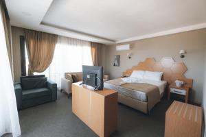 a hotel room with a bed and a tv at PALMİLA BUTİK OTEL in Silifke