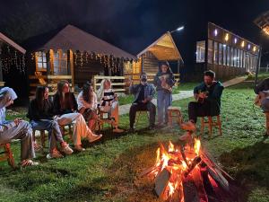 a group of people sitting around a fire at Căsuțele Doftanei in Teşila