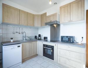 eine Küche mit Holzschränken, Spüle und Mikrowelle in der Unterkunft Le Logis de l'Arc - 5min Hypercentre - Max 6 Personnes in Troyes