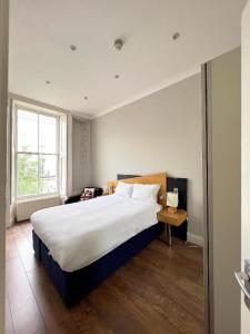 a bedroom with a large bed and a window at The Beverley Apartments London - Victoria in London