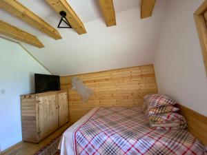 1 dormitorio con 1 cama en una habitación con paredes de madera en Căsuțele Doftanei en Teşila