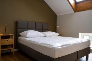 um quarto com uma cama com lençóis brancos e almofadas em ORKANA House em Olsztyn