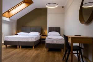 two beds in a room with a desk and a table at ORKANA House in Olsztyn