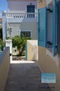 un callejón con persianas azules en un edificio blanco en Pension Panagiota, en Spetses