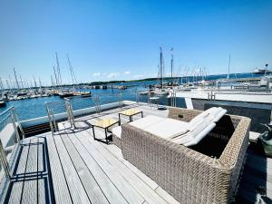 une terrasse avec des chaises et des tables sur un quai avec des bateaux dans l'établissement Floating Home Nr 1a, à Laboe