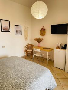 Schlafzimmer mit einem Bett, einem Tisch und einem TV in der Unterkunft B&B L'albero di Melograno in Seccheto