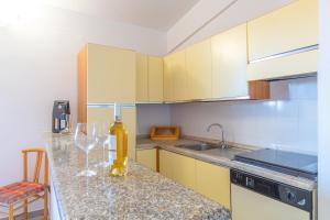 a kitchen with yellow cabinets and a counter with wine glasses at Myosotis Terrace by DomusAway in Porto San Paolo +9 photos