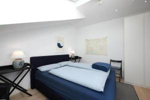 Cama azul en habitación con mesa y lámpara en Dock19, en Heikendorf
