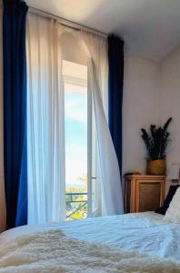 a bedroom with a bed and a large window at Blu Apartment in Historical Hunbury in Bordighera