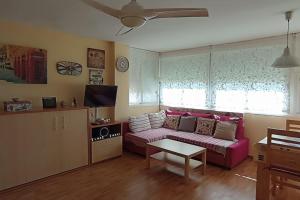 sala de estar con sofá rosa y TV en Estudio Rincon de la Victoria ( Malaga) en Rincón de la Victoria