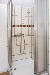 a shower in a bathroom with white tiles at Ferienwohnung am Sachsenring 